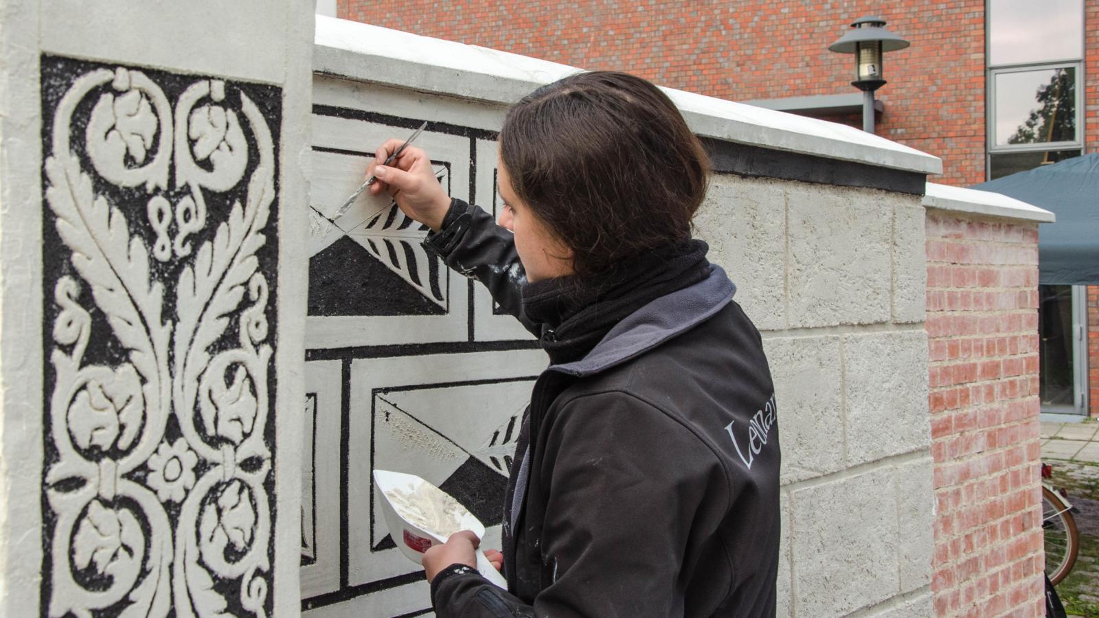 Studentin bt Malereitechniken an Au?ermauer auf dem Campus der FH Potsdam