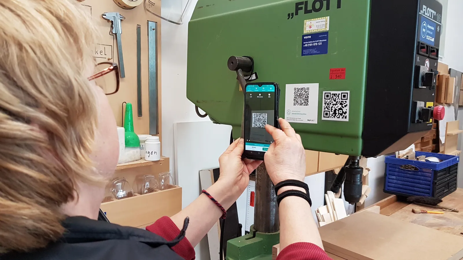 Person scannt QR-Code, der auf einer Maschine klebt.