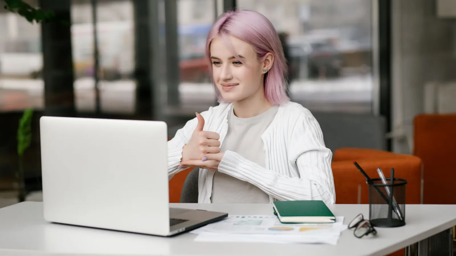 Junge geh?rlose Frau hat eine digitale virtuelle Online-Konferenz am Computer, benutzt Geb?rdensprache und zeigt Gesten am Bildschirm