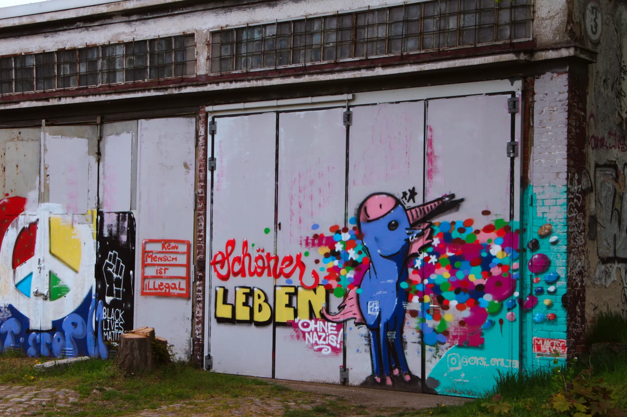 Graffiti auf der Panzerhalle mit Einhorn und Aufschrift "Sch?ner leben ohne Nazis" und gro?em Peace-Zeichen