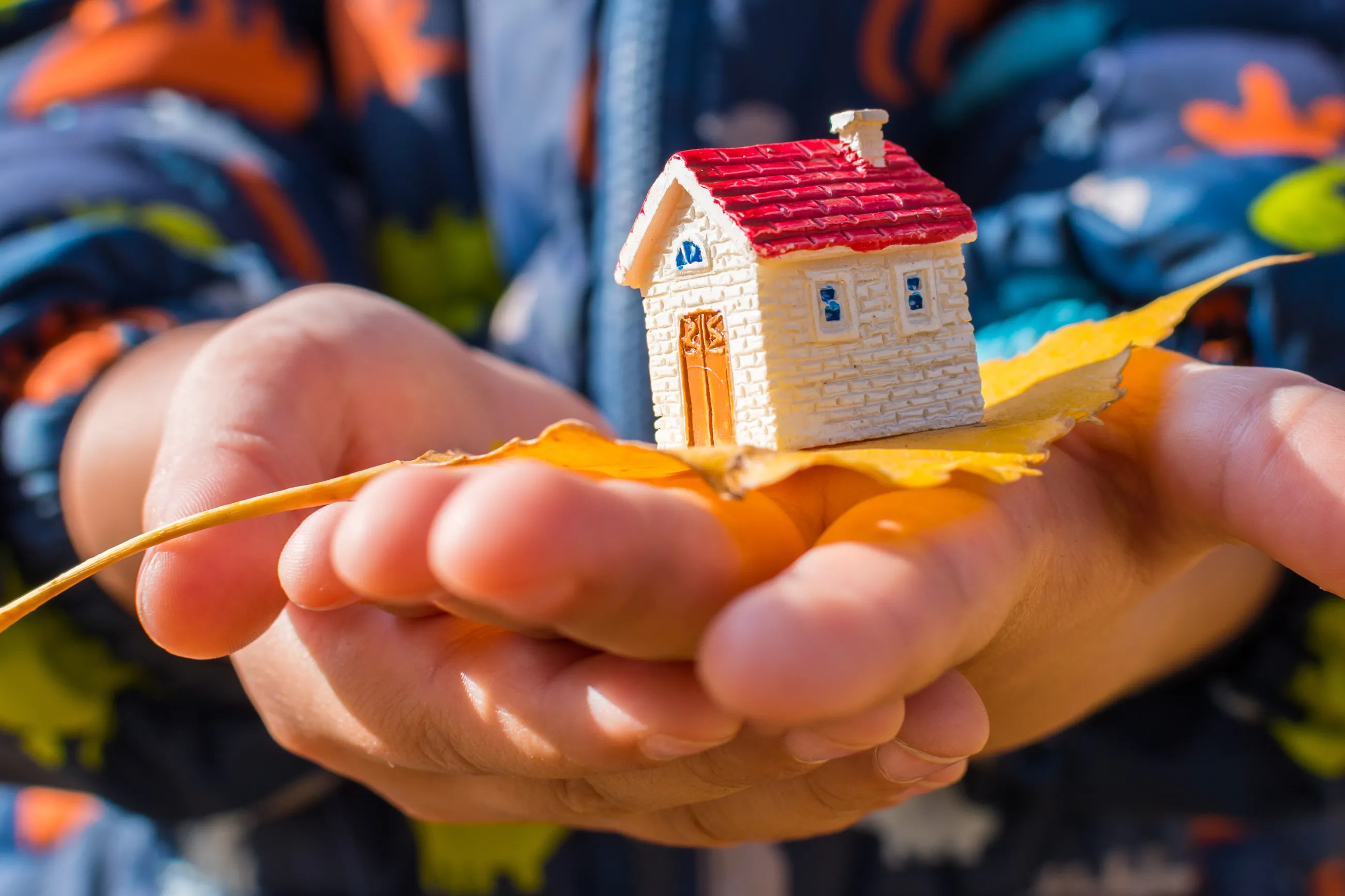 Zwei bereinander gelegte Kinderh?nde pr?sentieren ein Modellhaus