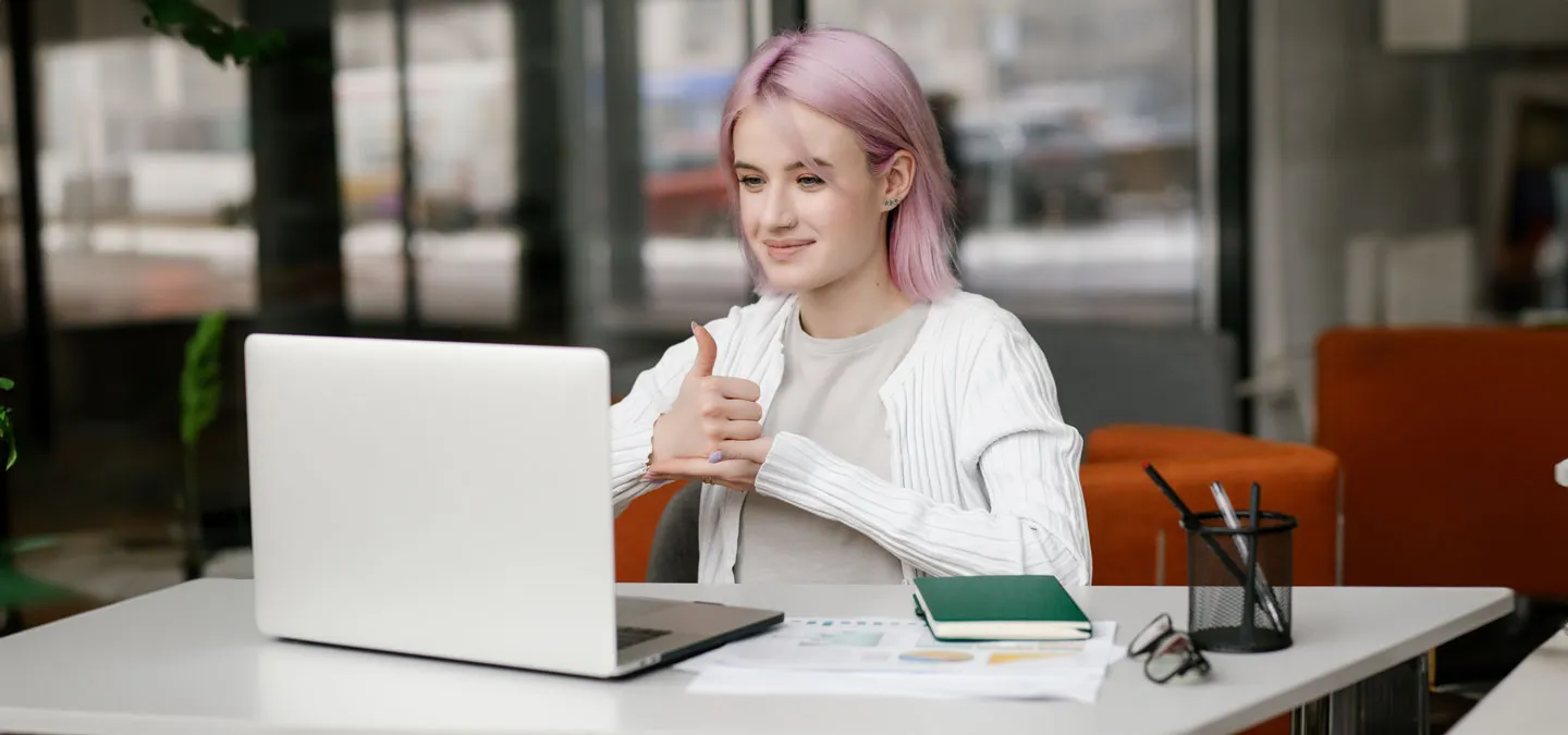 Junge geh?rlose Frau hat eine digitale virtuelle Online-Konferenz am Computer, benutzt Geb?rdensprache und zeigt Gesten am Bildschirm