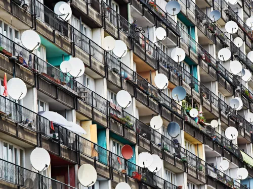 Fassade eines Wohnblocks mit vielen Balkons mit Satellitenschsseln